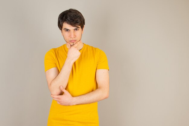 Portrait of a young man standing and looking at camera against gray.