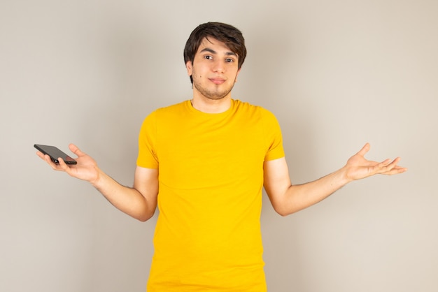 Portrait of a young man standing and looking at camera against gray.