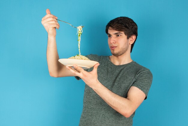 맛있는 국수 한 접시와 함께 서 있는 젊은 남자의 초상화.