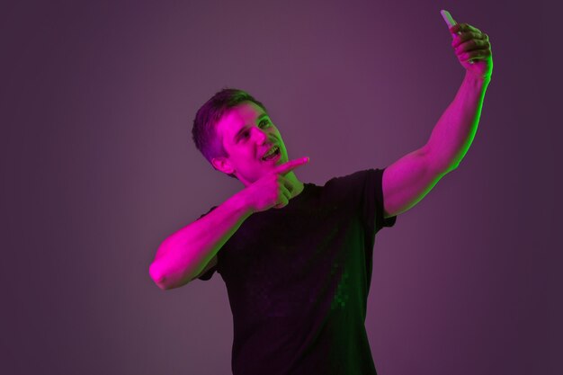 Portrait of young man taking selife with neon lights