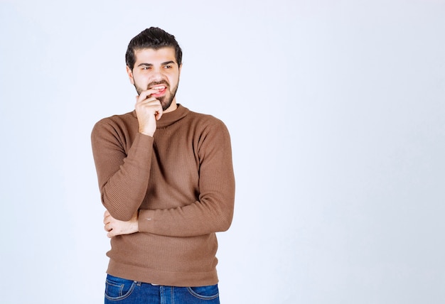 Free photo portrait of a young man thinking and standing against white wall.