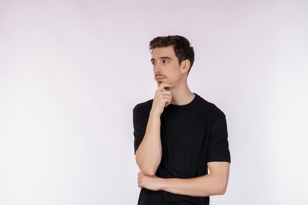 Portrait of young man thinking touching chin isolated over white background