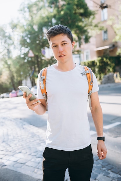 Free photo portrait of young man touching mobile screen at the street. sunny day