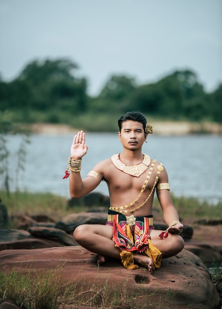 タイの自然の中でポーズをとる伝統的な衣装で若い男の肖像画