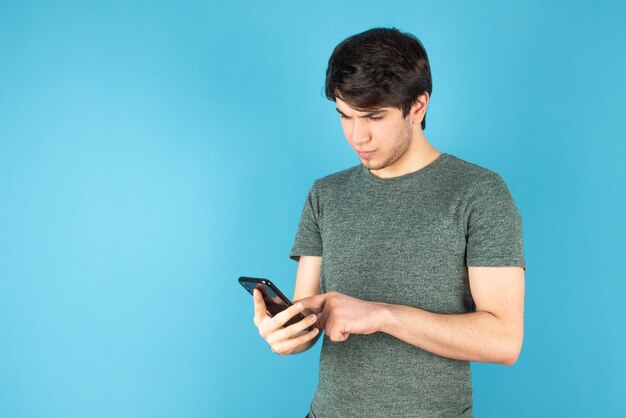 Portrait of a young man using a mobile phone against blue.