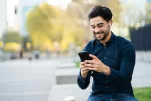 Free photo portrait of young man using a mobile phone while standing outdoors