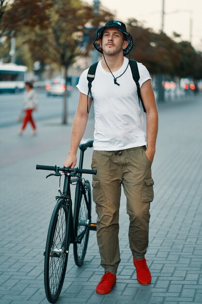 思慮深く古典的な自転車で歩く若い男の肖像