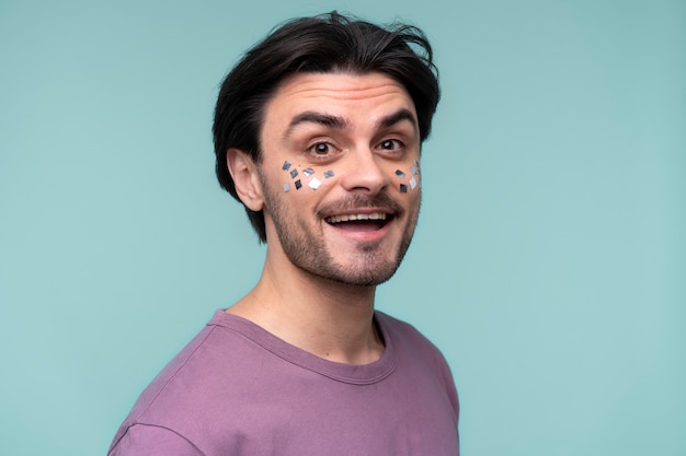 Free photo portrait of a young man wearing confetti on his face