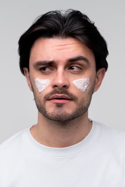 Portrait of a young man wearing moisturizer on his cheeks