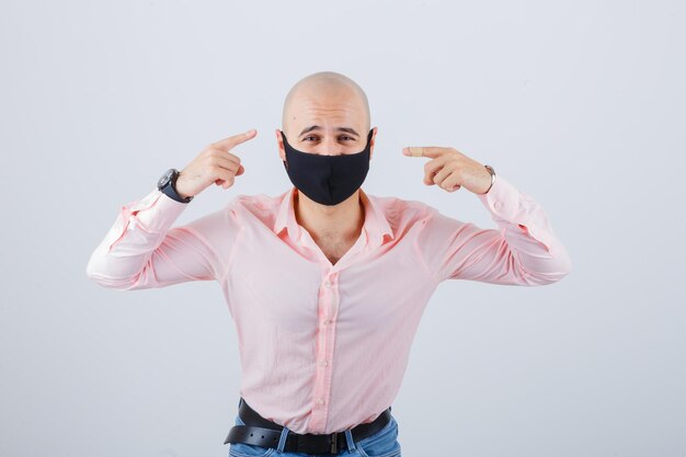 Portrait of young man wearing a protective mask and pointing himself