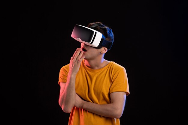 Portrait of young man wearing vr headset on dark wall