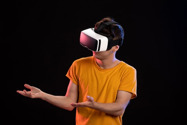 Portrait of young man wearing vr headset on dark wall