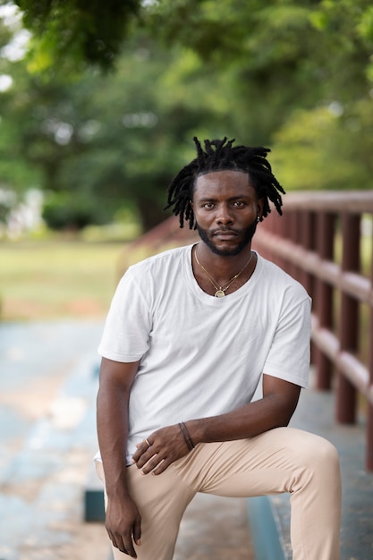 Portrait of young man with afro dreadlocks and white t-shirt outdoors