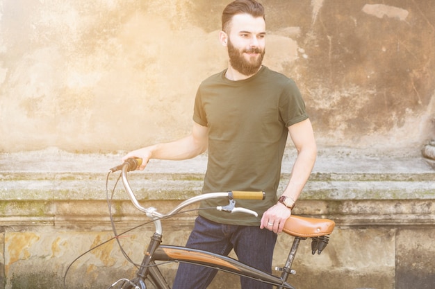 Ritratto di un giovane uomo con la bicicletta in cerca di distanza