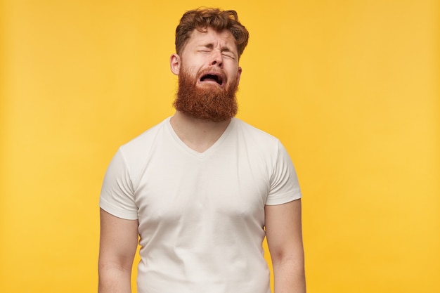 Free photo portrait of young man with big beard and red hair, wears blank t-shirt, feels depressed and tired