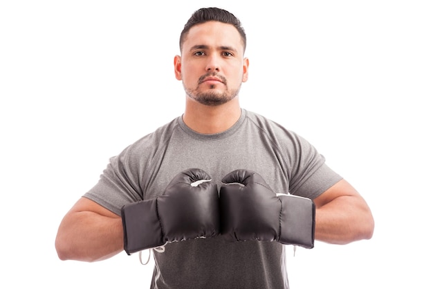 Портрет молодого человека в перчатках, выглядящего уверенно и серьезно и готового к боксу