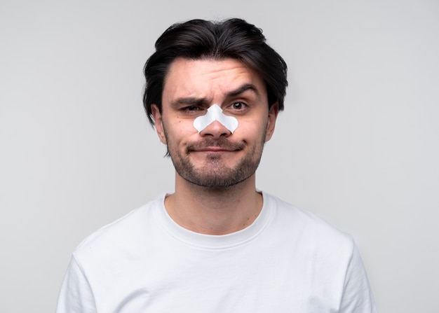 Portrait of a young man with his brow lifted and wearing a nose patch