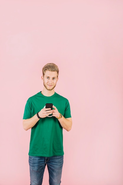 Портрет молодого человека с мобильного телефона, глядя на камеру