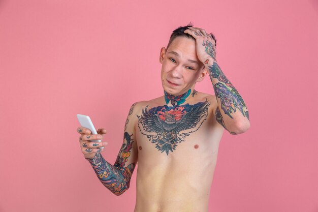 Portrait of young man with tattoos shocked reading news