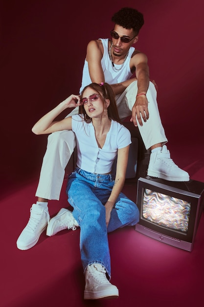 TV와 함께 포즈를 취하는 2000년대 패션 스타일의 젊은 남자와 여자의 초상화