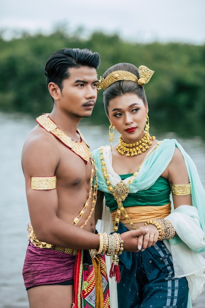 タイの自然の中でポーズをとる伝統的な衣装を着た若い男性と女性の肖像画