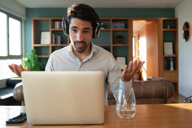Portrait of young man on a work video call with laptop from home. Home office concept. New normal lifestyle.