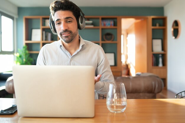 Портрет молодого человека на работе видеозвонка с ноутбуком из дома. Концепция домашнего офиса. Новый нормальный образ жизни.