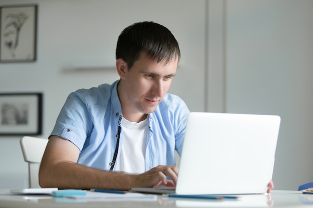 Portrait of young man working at the desk with laptop