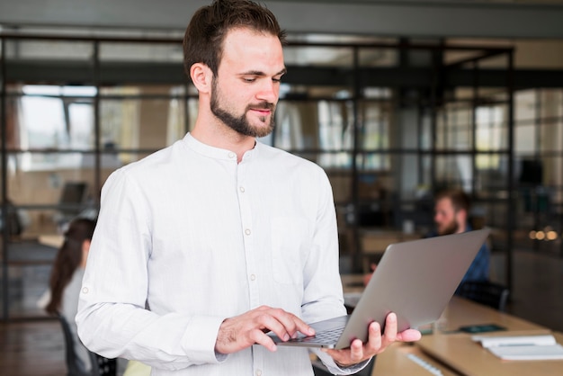 Free photo portrait of a young man working on laptop at workplace