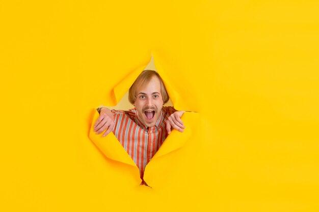 Portrait of young man on yellow torn breakthrought background