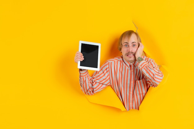 Free photo portrait of young man on yellow torn breakthrought background