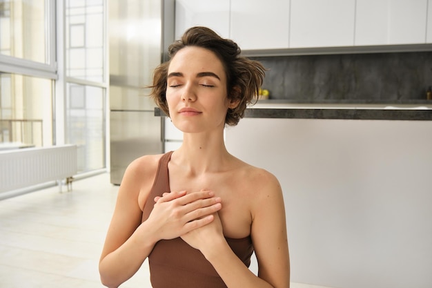 Foto gratuita ritratto di giovane donna consapevole apre il suo chakra facendo yoga sul tappetino di gomma a casa chiude gli occhi e sm