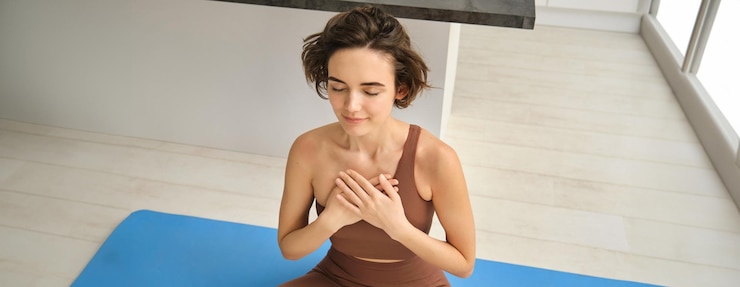 무료 Photo 집에서 고무 마트에서 요가를 하는 젊은 여성의 초상화 그녀의 차크라를 열고 눈을 감고