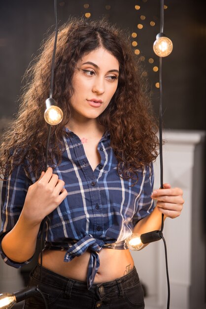 Portrait of a young model in plaid shirt posing near lamps