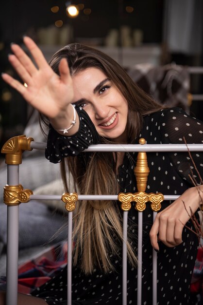 Portrait young model sitting on bed showing her hand to camera.