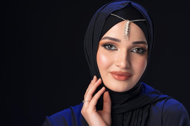Portrait of a young muslim woman in hijab on black background