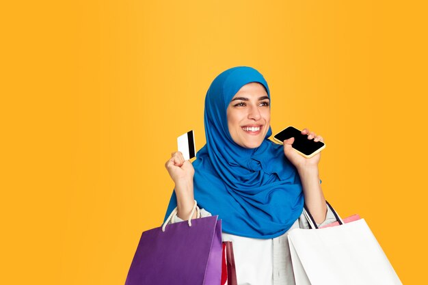 Portrait of young muslim woman isolated on yellow studio background