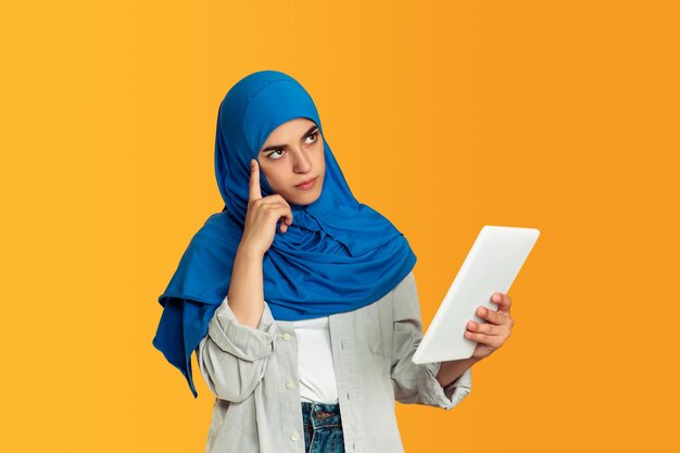 Portrait of young muslim woman isolated on yellow studio background