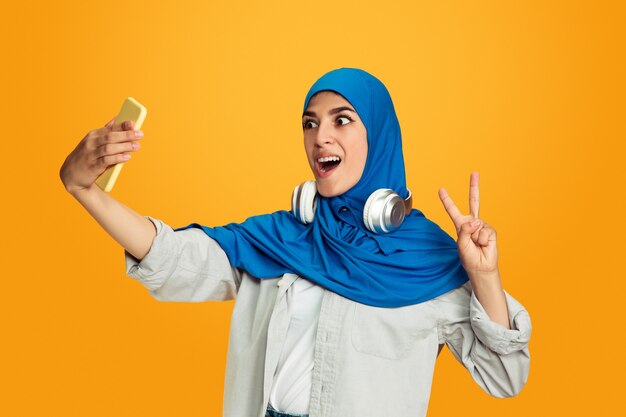 Portrait of young muslim woman isolated on yellow studio