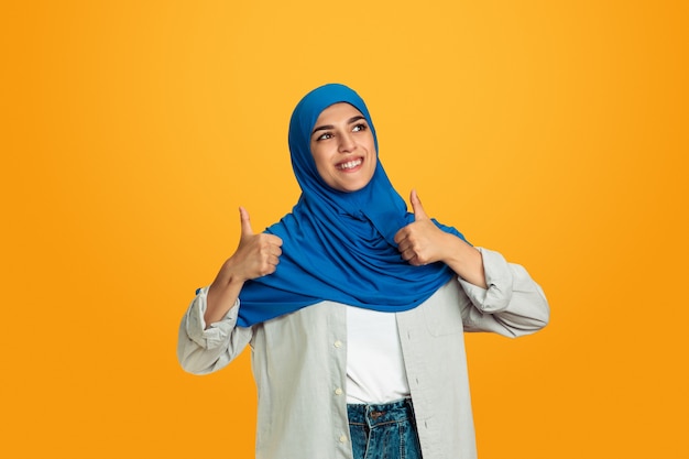 Portrait of young muslim woman on yellow background