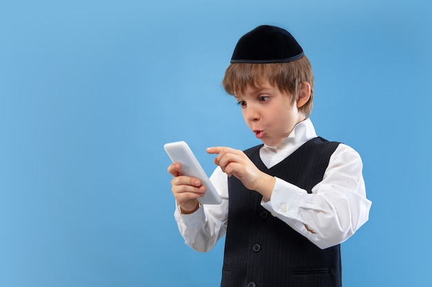 Free photo portrait of a young orthodox jewish boy isolated on blue  wall meeting the passover