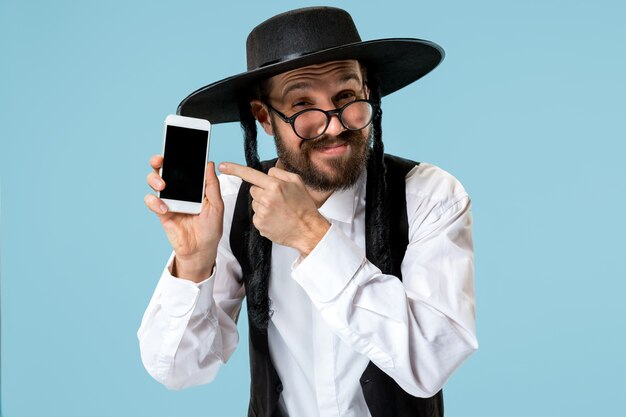 Portrait of a young orthodox jewish man with mobile phone at studio.