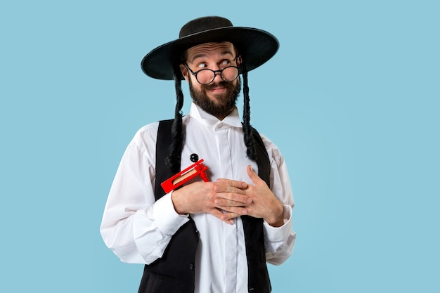 Foto gratuita ritratto di un giovane ebreo ortodosso con cricchetto grager in legno durante il festival purim