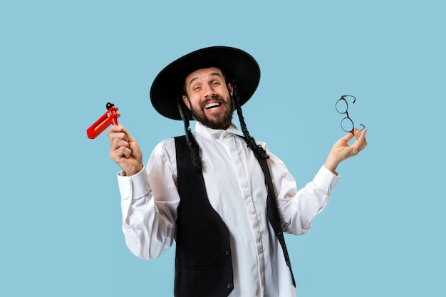 Portrait of a young orthodox jewish man with wooden grager ratchet during festival Purim. Holiday, celebration, judaism, tradition, religion concept.