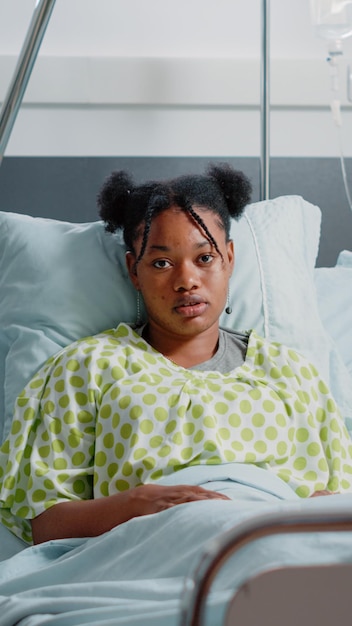 Free photo portrait of young patient in bed with iv drip bag, waiting on doctor to give medical assistance and cure disease. sick woman sitting in hospital ward with heart rate monitor to heal