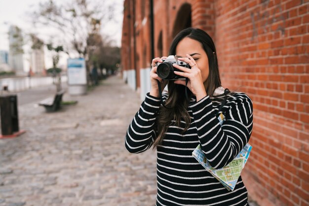 Портрет молодой женщины фотографа с помощью профессиональной цифровой камеры на открытом воздухе. Концепция фотографии