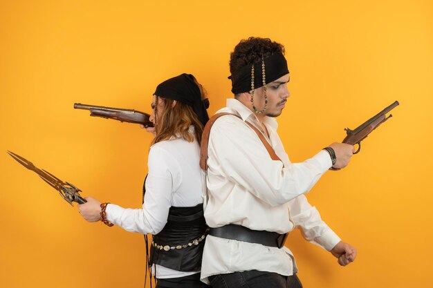 Portrait of young Pirates holding guns and stand pack to back. High quality photo