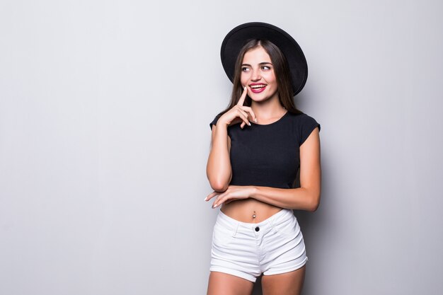 Portrait of a young playful woman with floppy hat on gray background