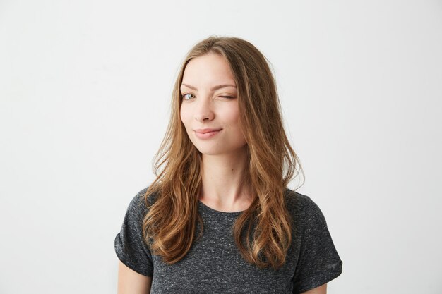 Portrait of young positive girl smiling winking .