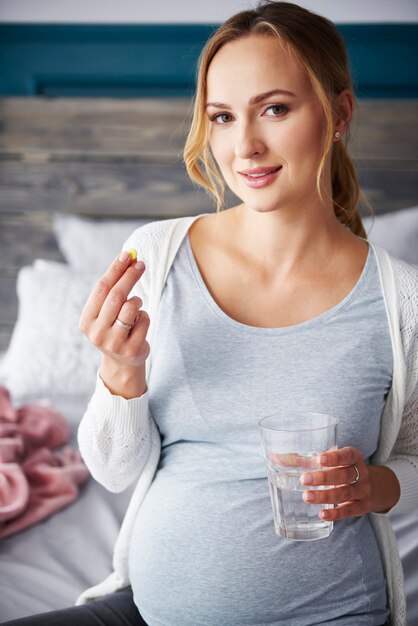 Портрет молодой беременной женщины, принимающей лекарство